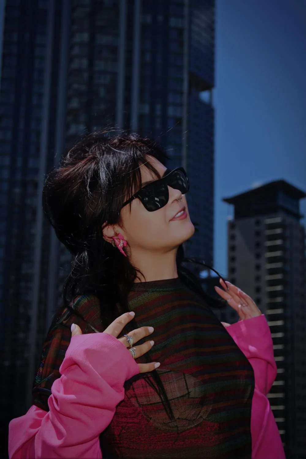 Andreea in a pink blazer against city buildings
